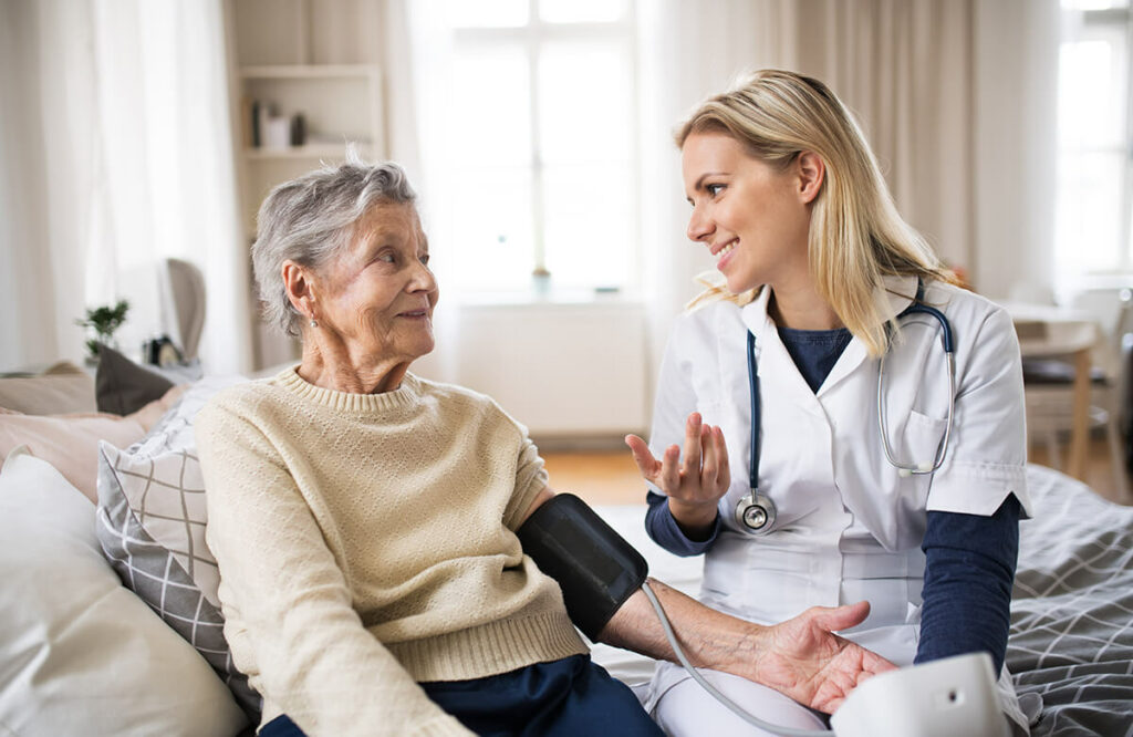 A health visitor measuring a blood pressure of a senior woman at home