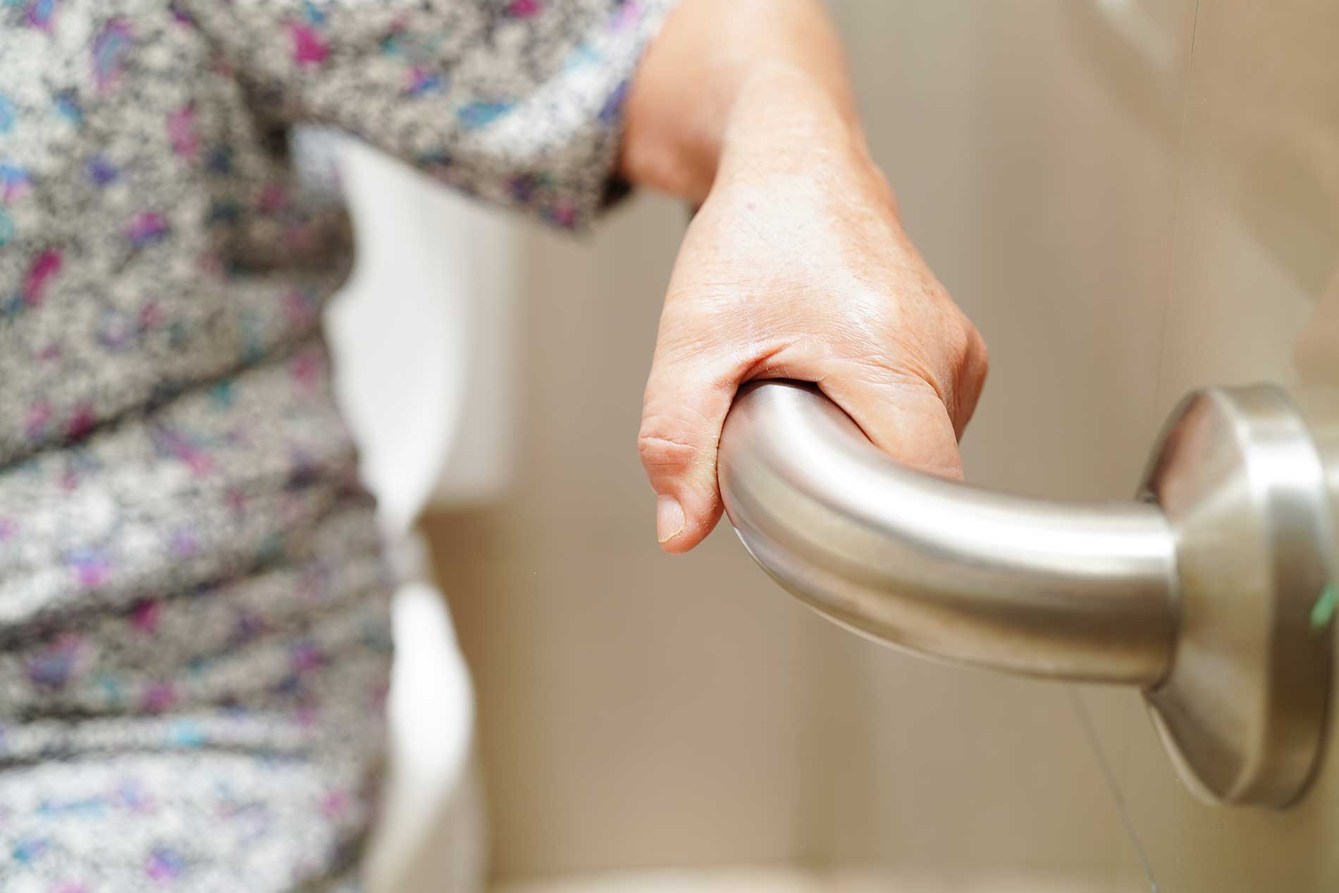 elderly woman holding onto a bar for support