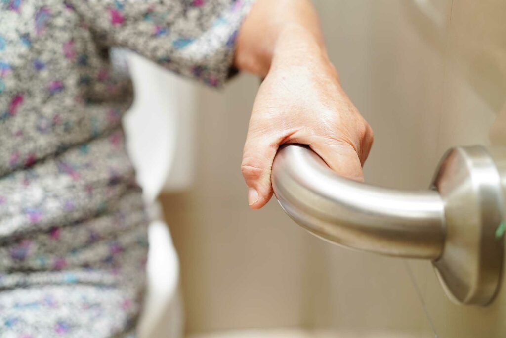 elderly woman holding onto a rail for support